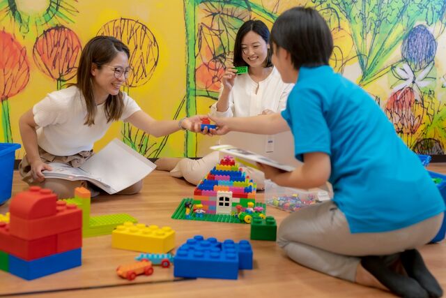 Japanese staff training young mothers to facilitate preschool lessons as part of their hybrid careers.